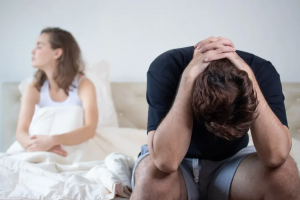 Hombre con disfunción eréctil preocupado en la cama junto a su pareja en Barcelona